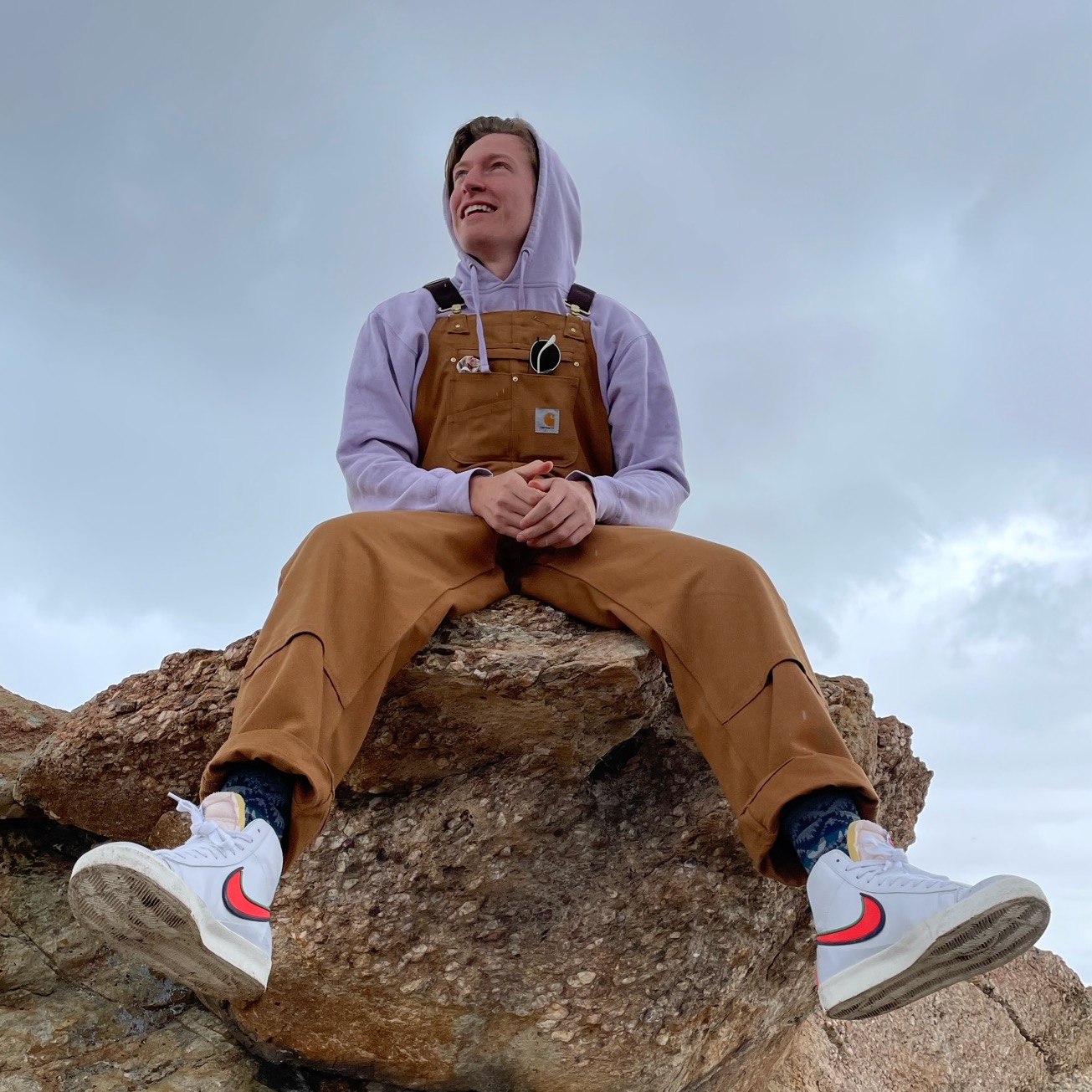 A picture of me sitting on a rock, wearing a hoodie and overalls